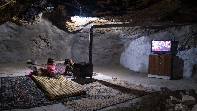 Children watch television with electricity generated from solar panels at their home inside a cave in January 2023. Children watch television with electricity generated from solar panels at their home inside a cave in January 2023.