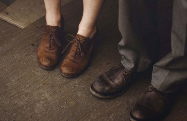 This may contain: two people standing next to each other wearing brown shoes