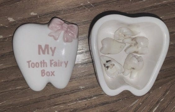 This may contain: two tooth shaped dishes with pink bows on them sitting on a wooden table next to each other