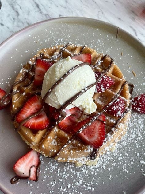 This may contain: a waffle topped with strawberries and ice cream This may contain: a waffle topped with strawberries and ice cream