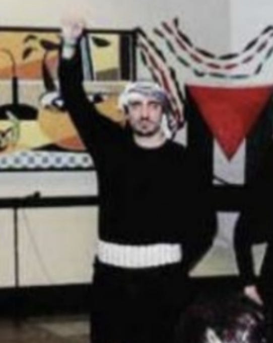 First image shows a middle-aged man with short dark hair and mustache wearing a dark blue suit white shirt and yellow tie with polka dots standing in front of two American flags against a light gray background in a formal setting. Second image depicts a man with short dark hair and mustache dressed in black long-sleeve shirt black pants and white belt wearing a red and white keffiyeh headscarf raising his right arm upward with palm open in a room with beige walls and abstract colorful paintings on the walls including red orange and multicolored striped artwork.