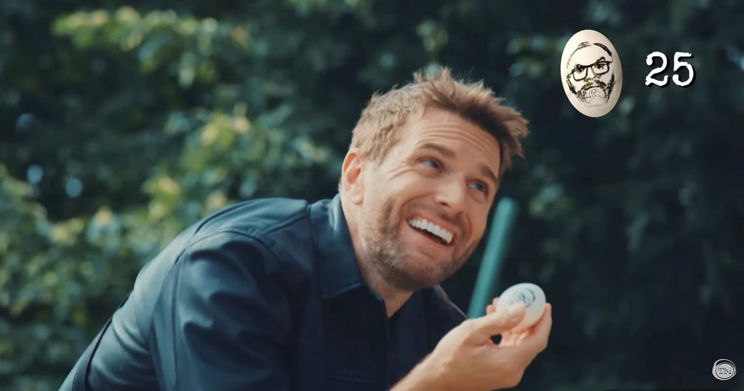 Joel Dommett holds an egg stamped with the likeness of Greg Davies