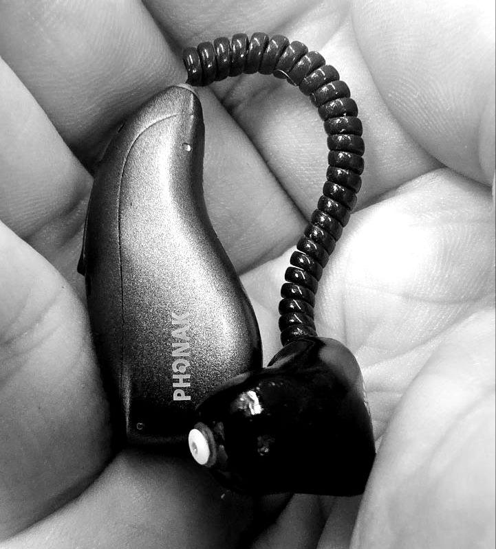 A black and white image showing a Phonak hearing aid in Jamie's hand