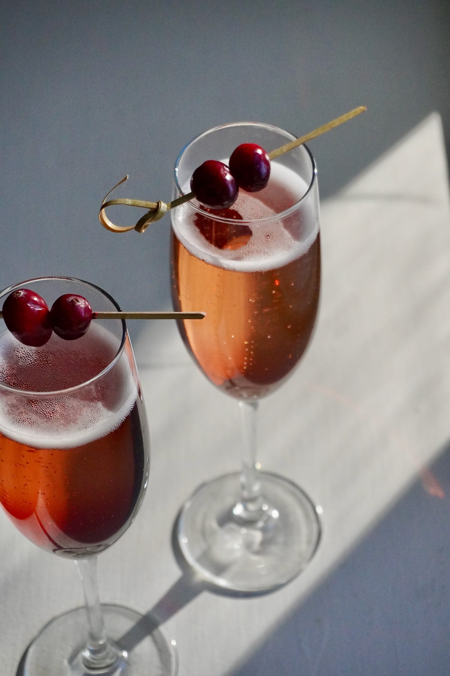 Elegant French Kir Royale cocktail with Champagne, crème de cassis, and fresh cranberry garnish — festive holiday apéritif for Friendsgiving.