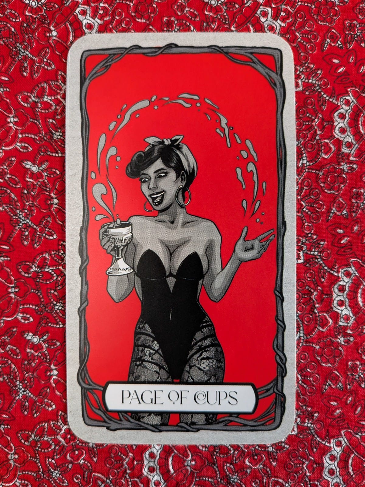 Page of Cups from Michelle Lodge’s Bad Witch Tarot, showing a smiling woman holding a goblet surrounded by a circular splash of water. Page of Cups from Michelle Lodge’s Bad Witch Tarot, showing a smiling woman holding a goblet surrounded by a circular splash of water.