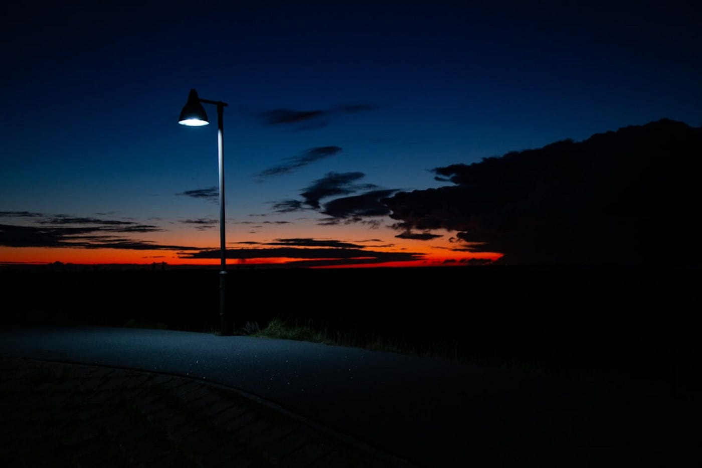 a lone lamppost lighting dimly at dusk. a lone lamppost lighting dimly at dusk.