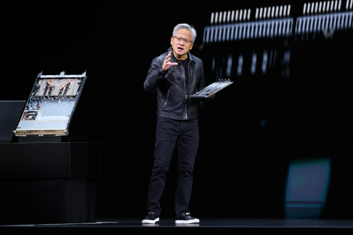 Nvidia CEO Jensen Huang holding a circuit board while giving a keynote address.