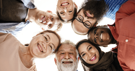 A circle of people of different genders and skin colours in a huddle.