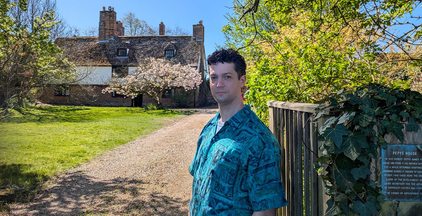 Me standing at the end of a long driveway that leads down to Pepys House, a long Tudor building. There is a tree in blossom just before the front door. A sign by the gate says "PEPYS HOUSE", and explains that the house belonged to Robert Pepys before he left it to his brother John and, eventually, his nephew Samuel. The plaque also states that the poet John Drinkwater was once a tenant. Me standing at the end of a long driveway that leads down to Pepys House, a long Tudor building. There is a tree in blossom just before the front door. A sign by the gate says "PEPYS HOUSE", and explains that the house belonged to Robert Pepys before he left it to his brother John and, eventually, his nephew Samuel. The plaque also states that the poet John Drinkwater was once a tenant.