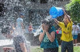Celebration of Vardavar in Armenia with child wearing yellow t-shirt pouring water from a blue pail on another