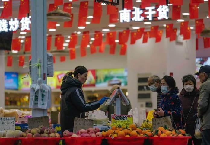 A person wearing a face mask and gloves at a fruit stand

Description automatically generated