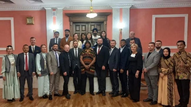 Des hommes en costumes et des femmes en robe élégante posent ensemble les bras ballants