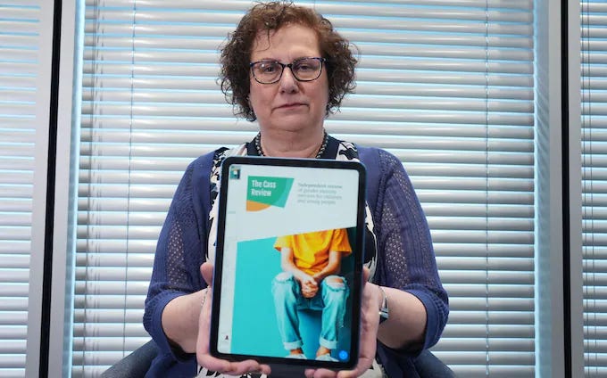Dr Cass holds up a tablet computer with the cover of the review Dr Cass holds up a tablet computer with the cover of the review