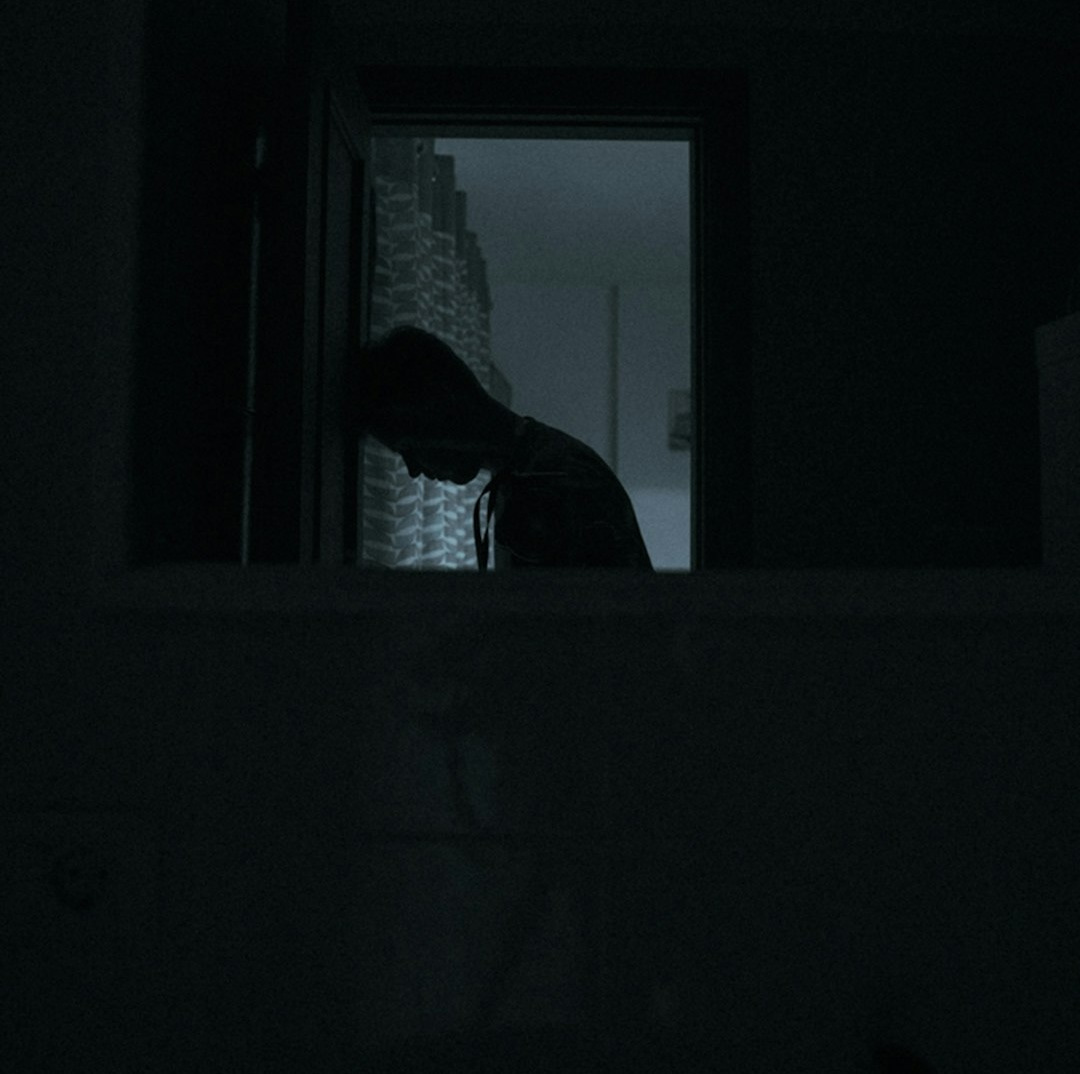 person in black jacket standing near window