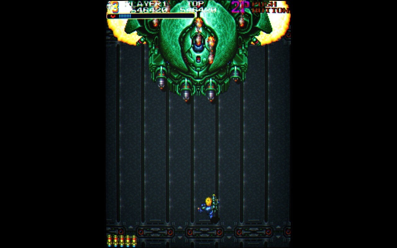 A screenshot of a boss from Out Zone, a huge tank-like ship with some mech characteristics, with four missile bays and destroyed cannons on the left and right. The "eye" in the center is its weak point, but only at specific moments in the fight.
