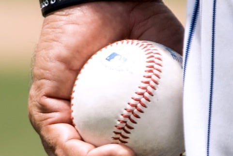 man holding two white baseballs