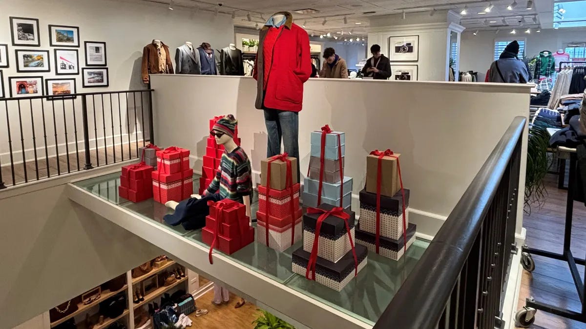 Interior J. Crew storefront with mannequins modelling red winter clothing next to holiday gifts
