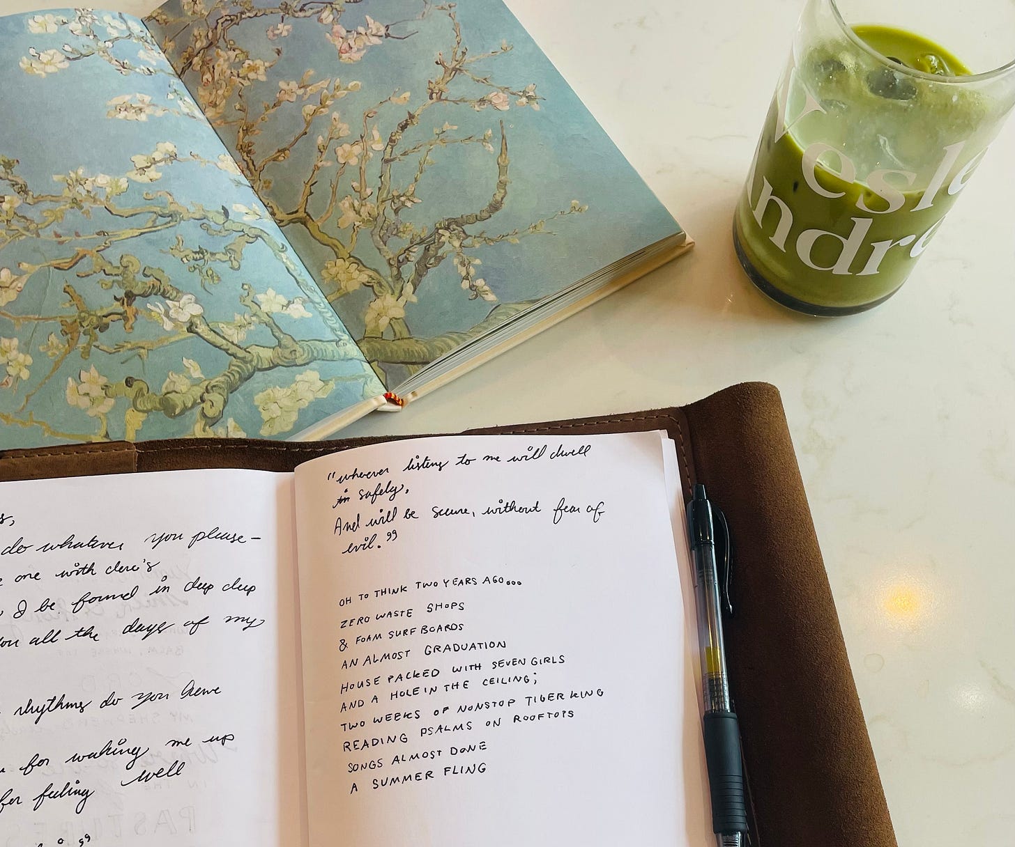 Picture shows an art book with a matcha and a journal of poems open at a coffee shop