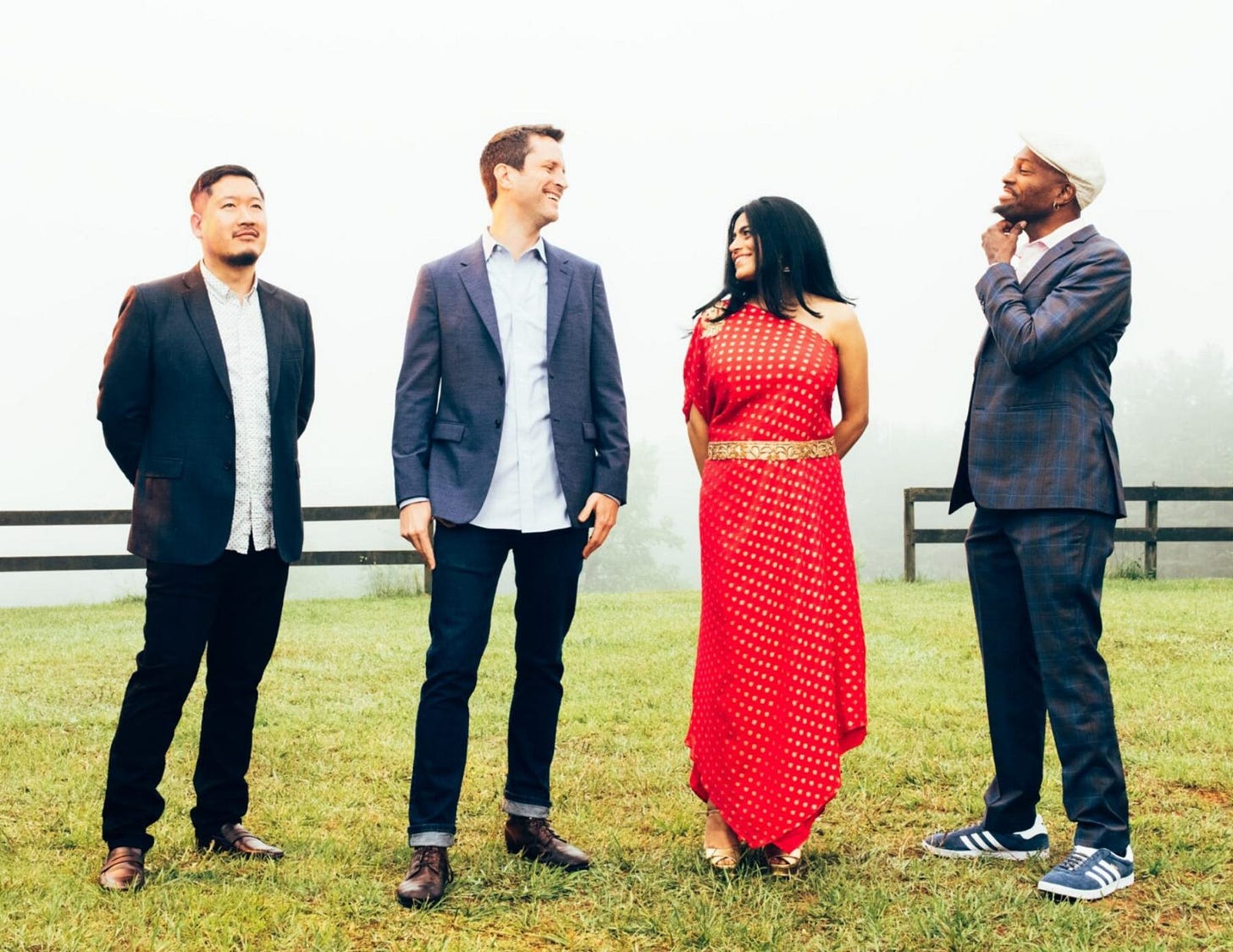 The group of American Patchwork Quartet stands in a green field smiling with each other The group of American Patchwork Quartet stands in a green field smiling with each other