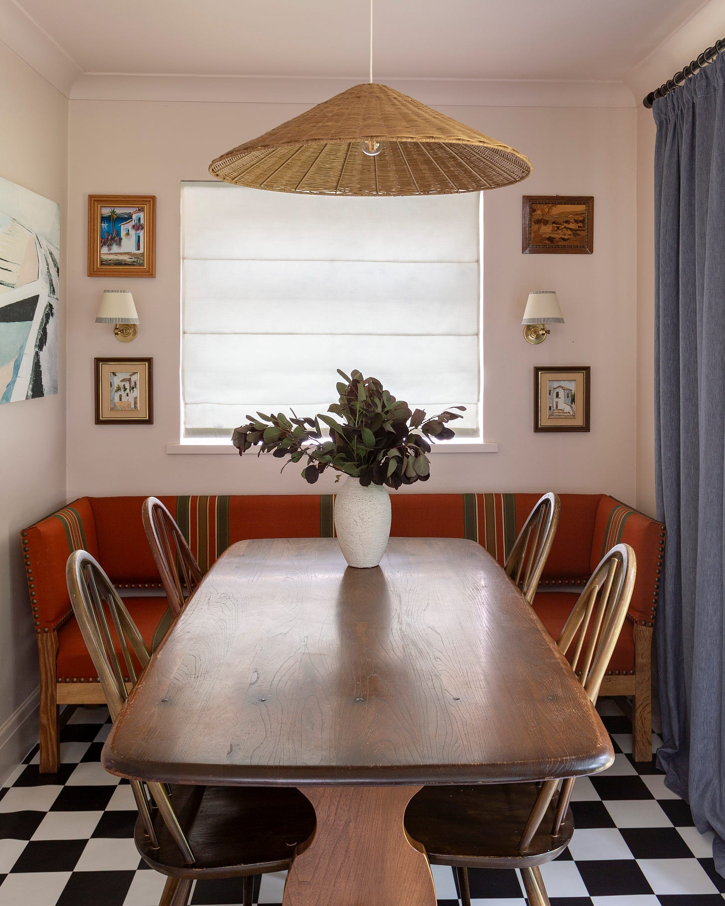 Dining room with soft pink walls, dining table and bench, chequerboard floors