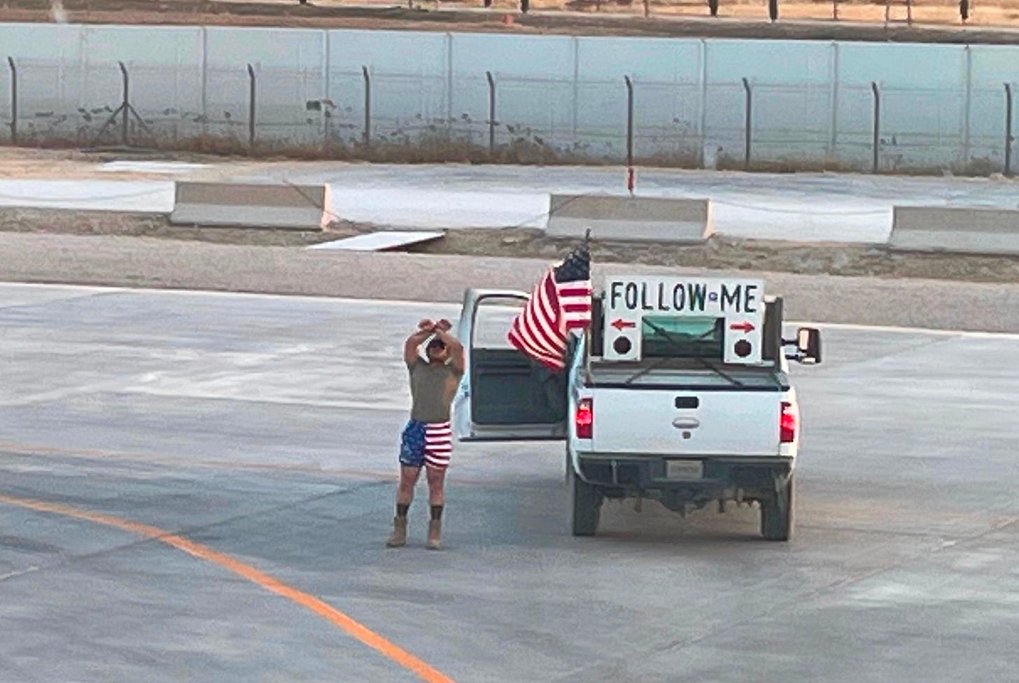 military aircraft marshaller directs aircraft to stop while sporting American flag on his "follow me" truck and shorts military aircraft marshaller directs aircraft to stop while sporting American flag on his "follow me" truck and shorts