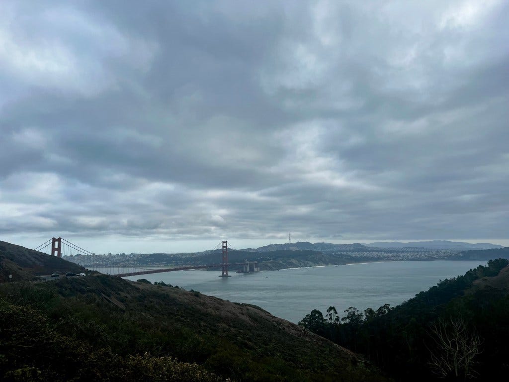 Cloudy blue-gray skies over the Golden Gate bridge, the sea a steel gray and the hills dull in the covered evening light.