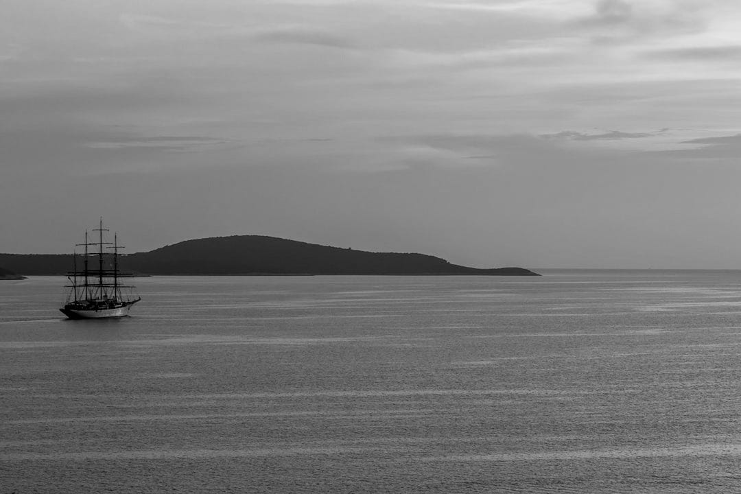 photo of black sailing boat on body of water photo of black sailing boat on body of water