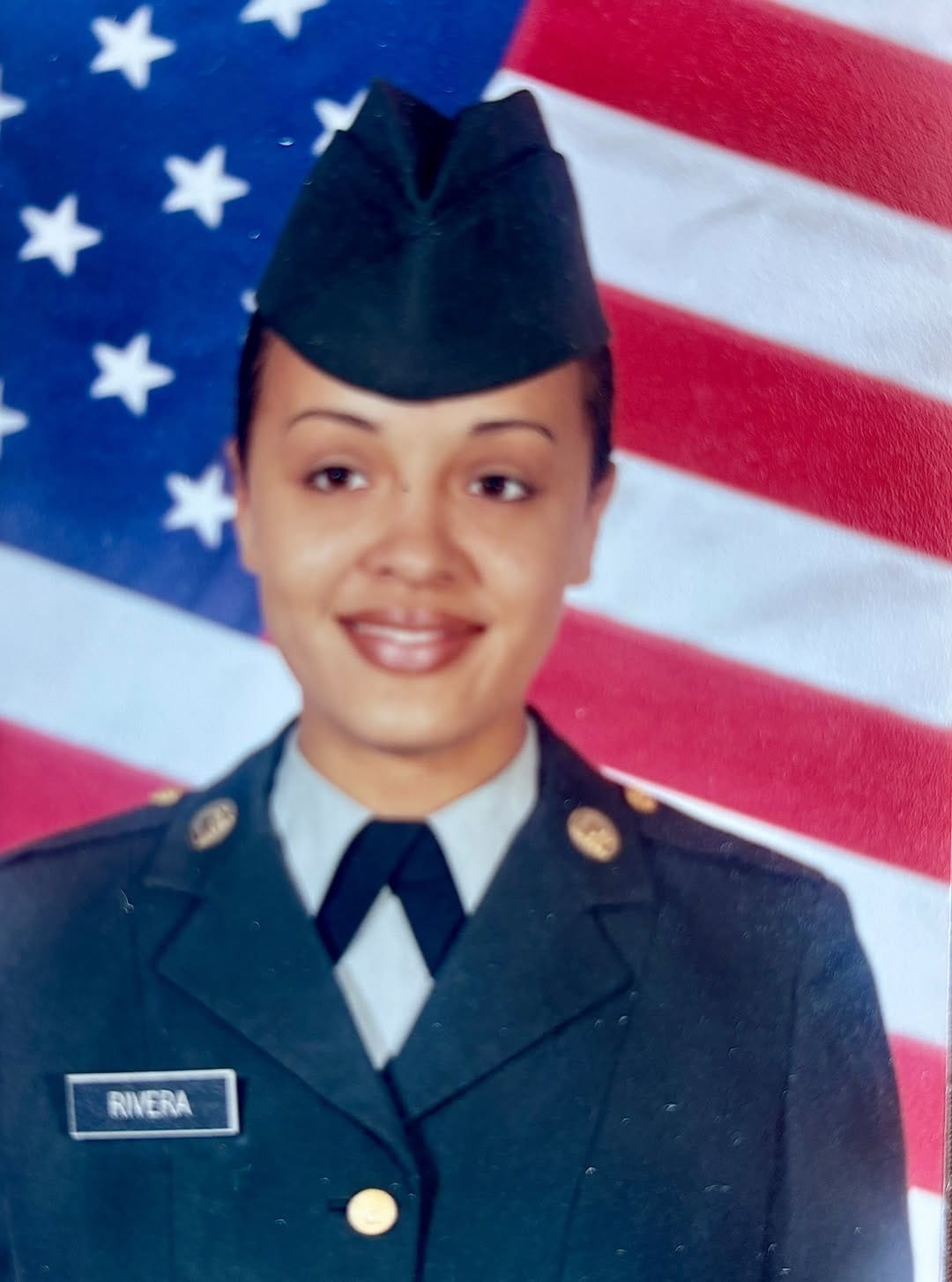 Marta Rivera Diaz in uniform in front of an American Flag Marta Rivera Diaz in uniform in front of an American Flag