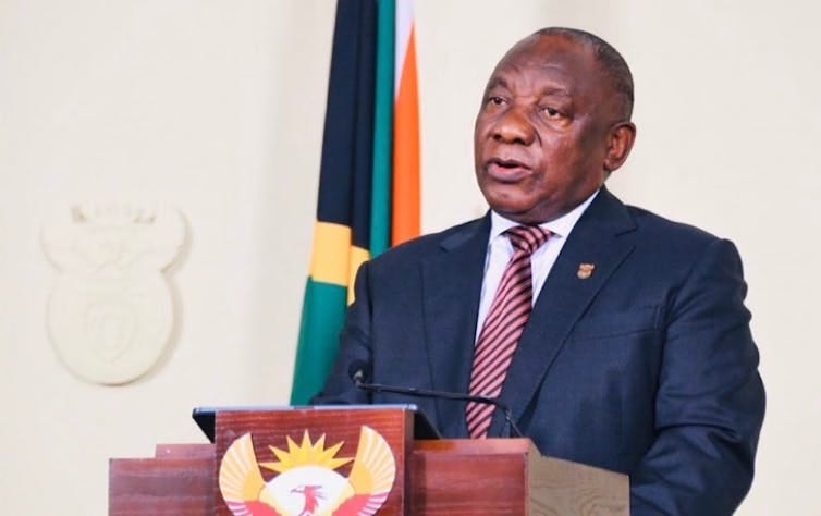 President Cyril Ramaphosa, wearing a suit and tie, speaks at a podium with the South African coat of arms. President Cyril Ramaphosa, wearing a suit and tie, speaks at a podium with the South African coat of arms.