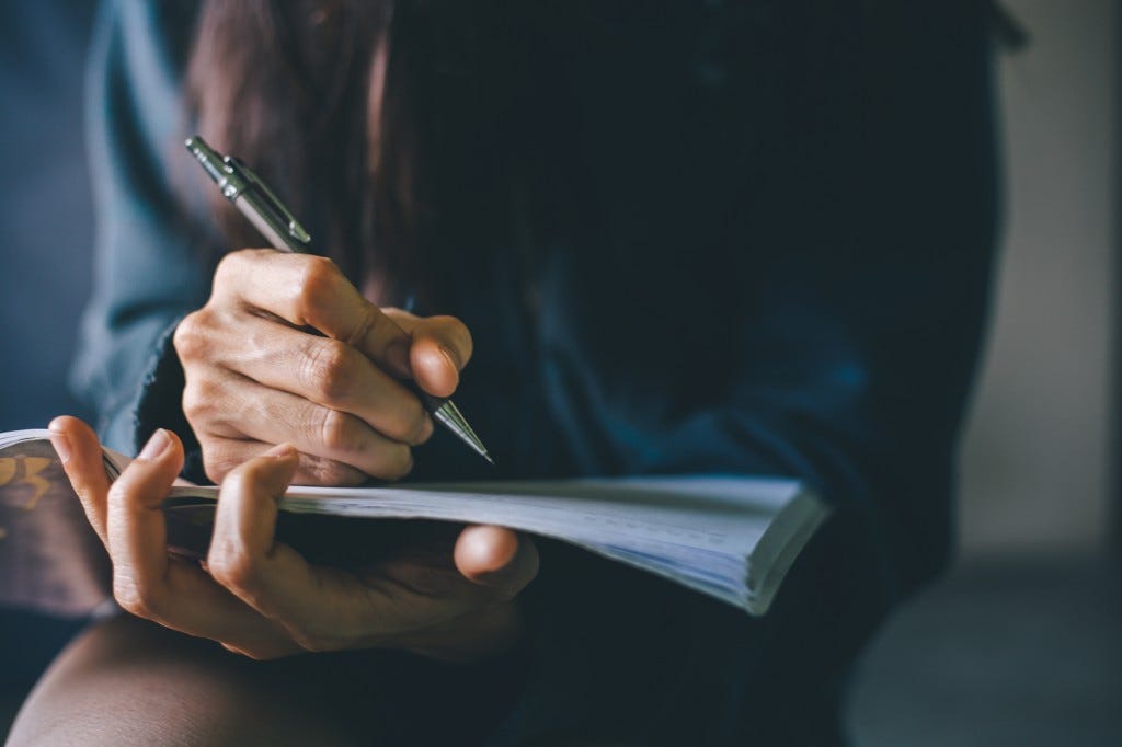Adults writes in a notebook. 
