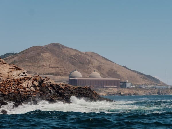 Diablo Canyon seen from across a body of water. There is a big hill behind it. Diablo Canyon seen from across a body of water. There is a big hill behind it.