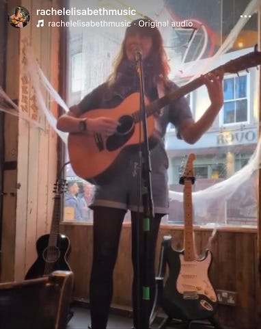 Rachel singing and playing an acoustic guitar