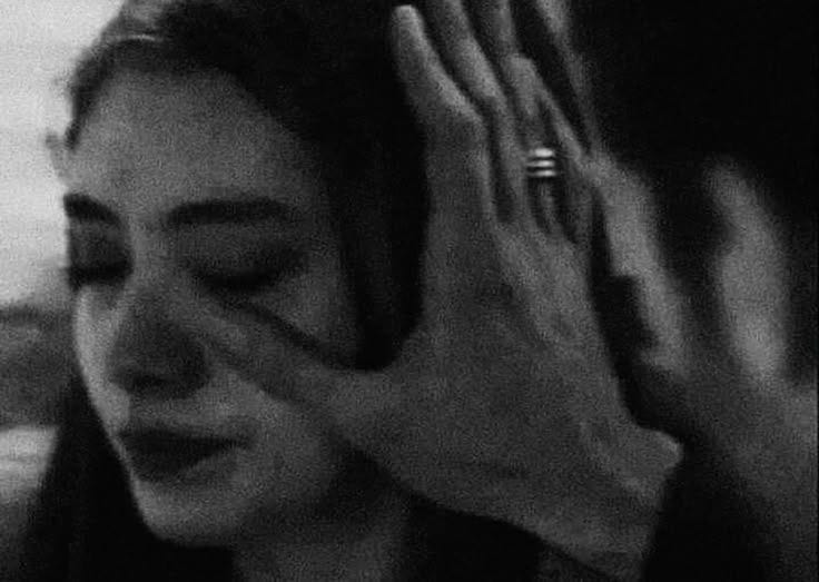a woman holding her hands up in front of her face while she is listening to music
