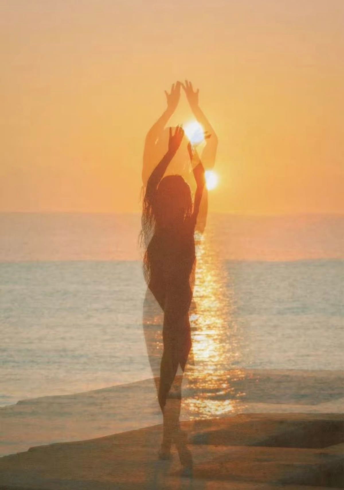 a beautiful slightly blurry photo of a woman walking on the beach during sunset with her hands in the air and the ocean behind her