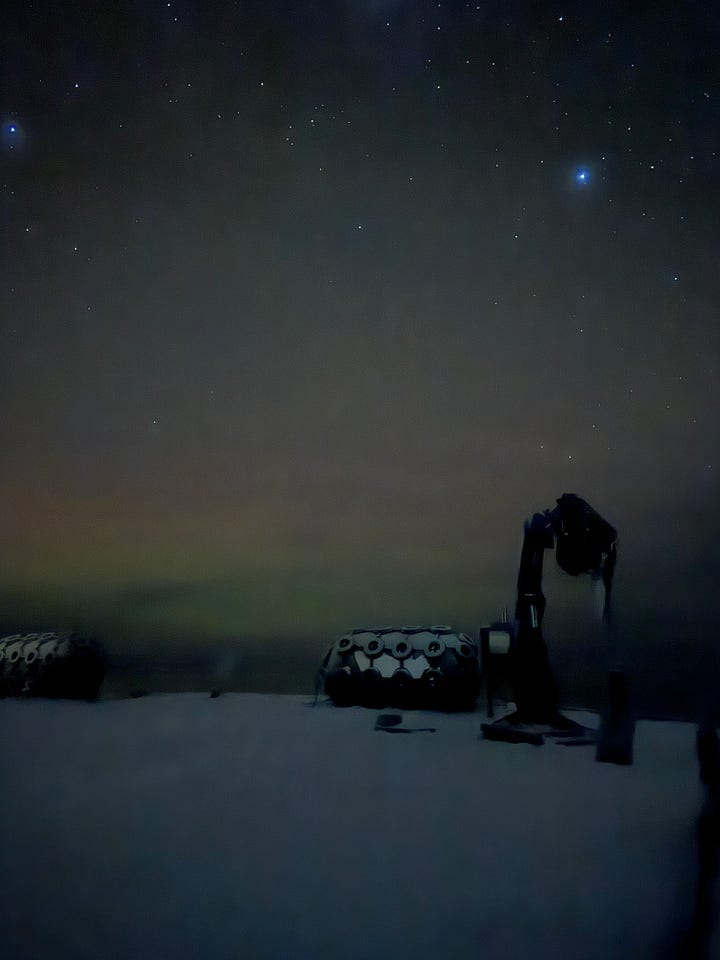 Images show the green haze of the Southern Lights over the sea.