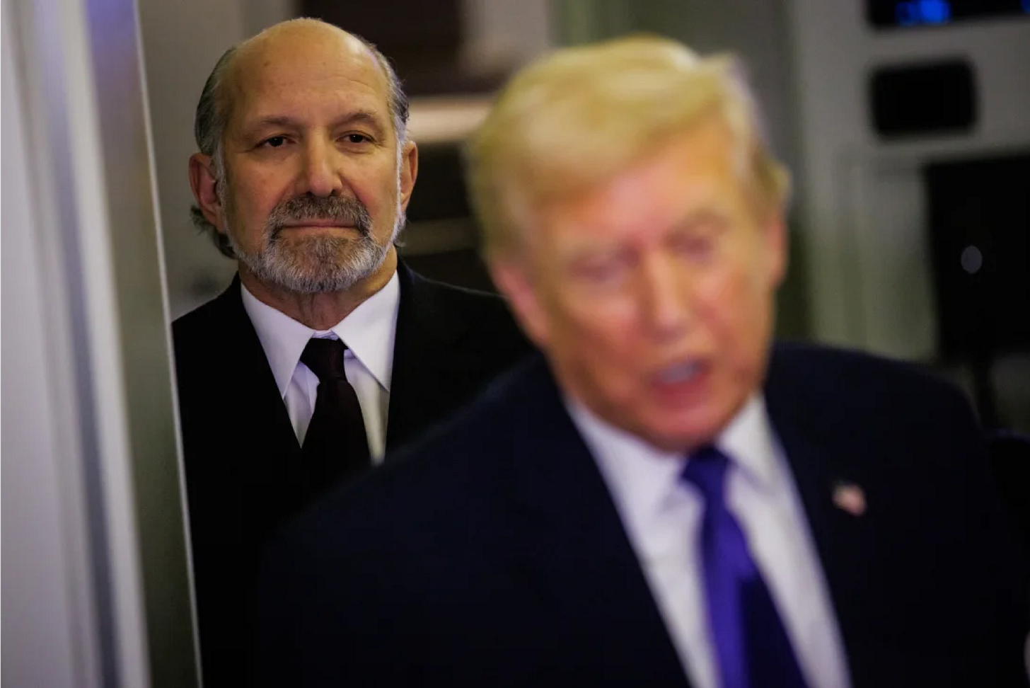 Secretary of Commerce Howard Lutnick stands behind President Donald Trump as he speaks with reporters while aboard Air Force One on February 6. Secretary of Commerce Howard Lutnick stands behind President Donald Trump as he speaks with reporters while aboard Air Force One on February 6.
