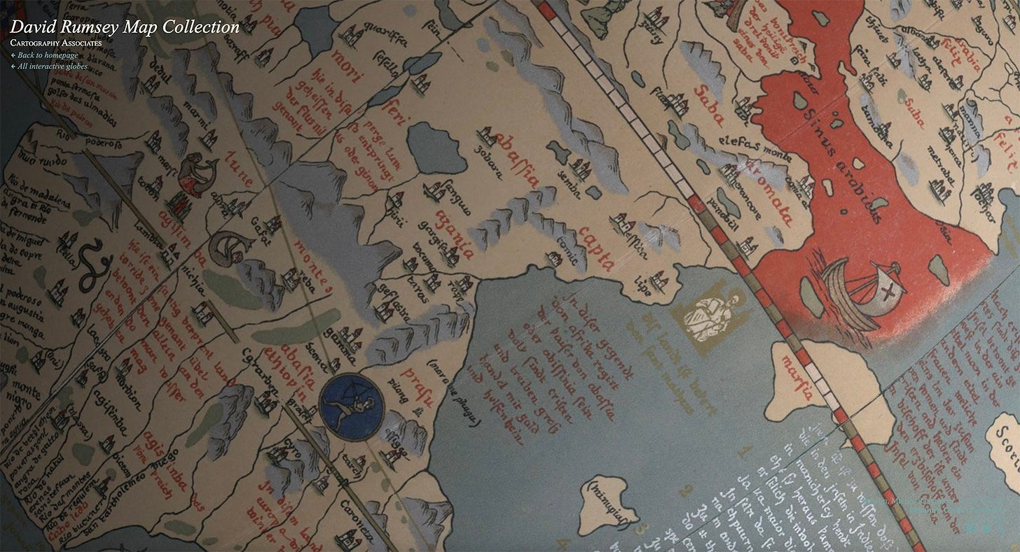Close-up of the globe’s painted map with red and black lettering, tiny buildings, mountains, ships, and sea creatures.