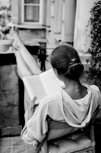 This may contain: a woman sitting in a chair reading a book