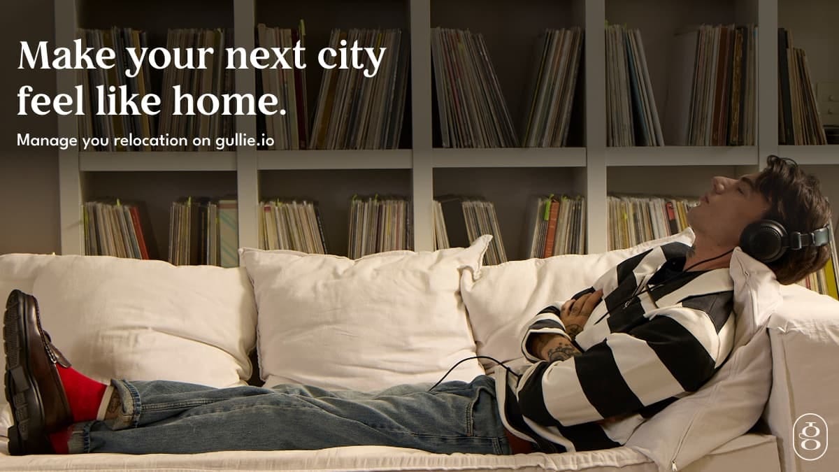 A man lying on a sofa with headphones on in front of shelves of records, with the headline Make your next city feel like home