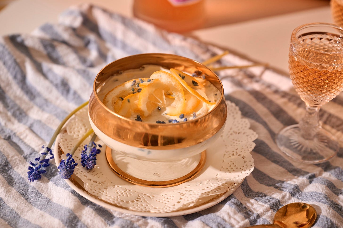 Lemon & Violet icebox cake served in a glass bowl with gold spoon and aperitif on a striped linen. Lemon & Violet icebox cake served in a glass bowl with gold spoon and aperitif on a striped linen.
