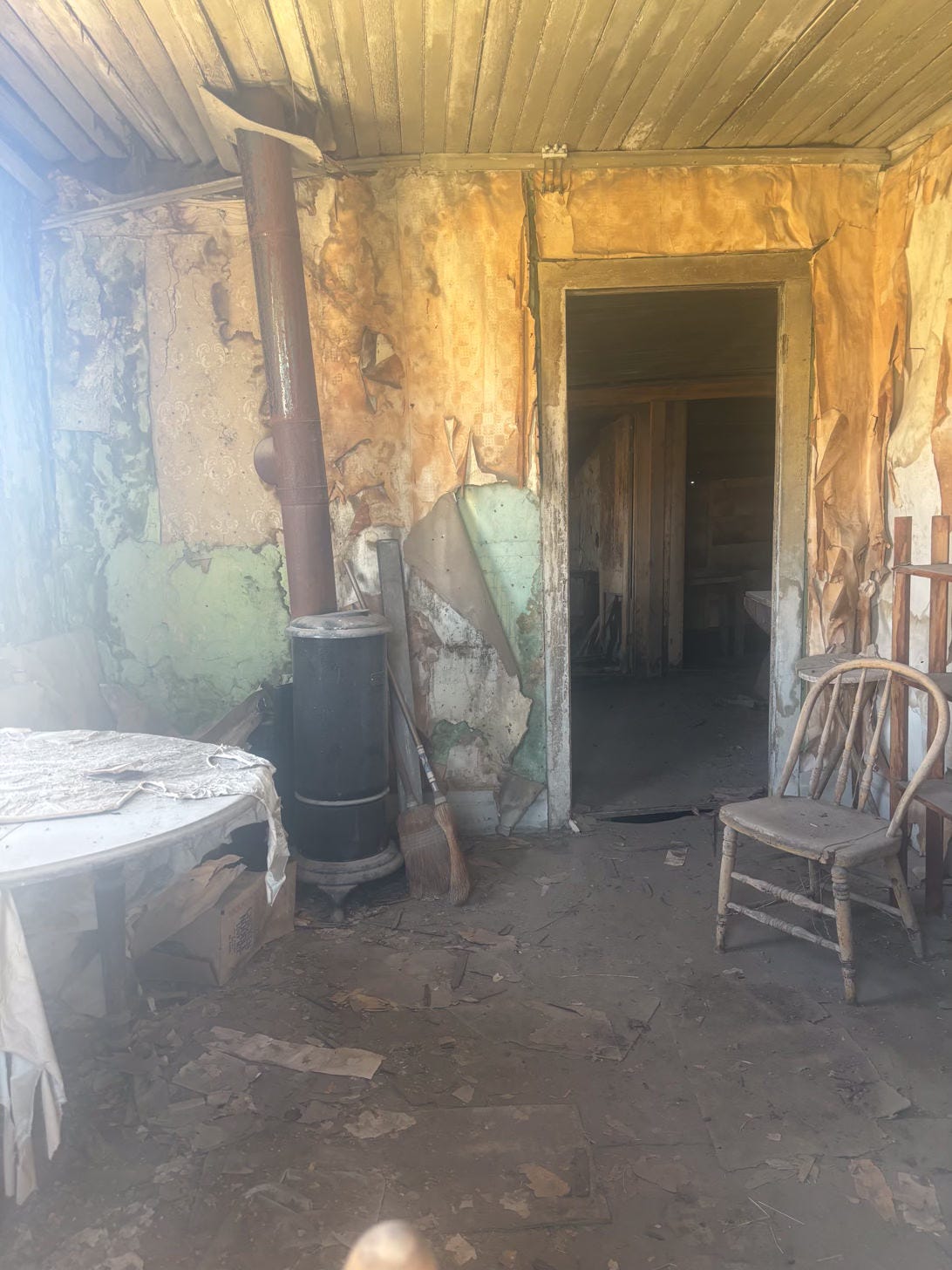 interior of room with old-fashioned stove, table and chair in decaying condition