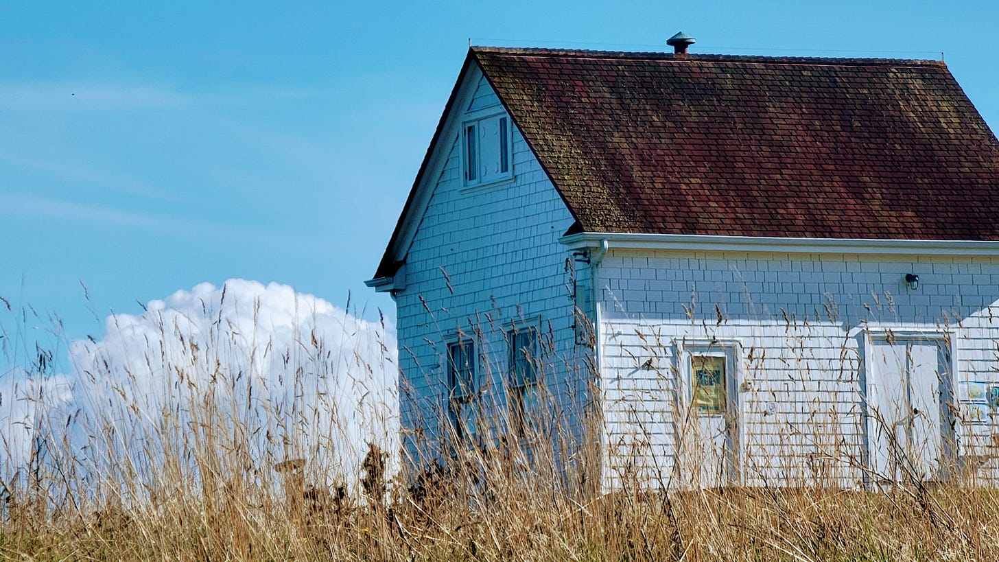 A white building with a reddish roof sitting amid grasslands - against a backdrop of sky and cloud. A white building with a reddish roof sitting amid grasslands - against a backdrop of sky and cloud.