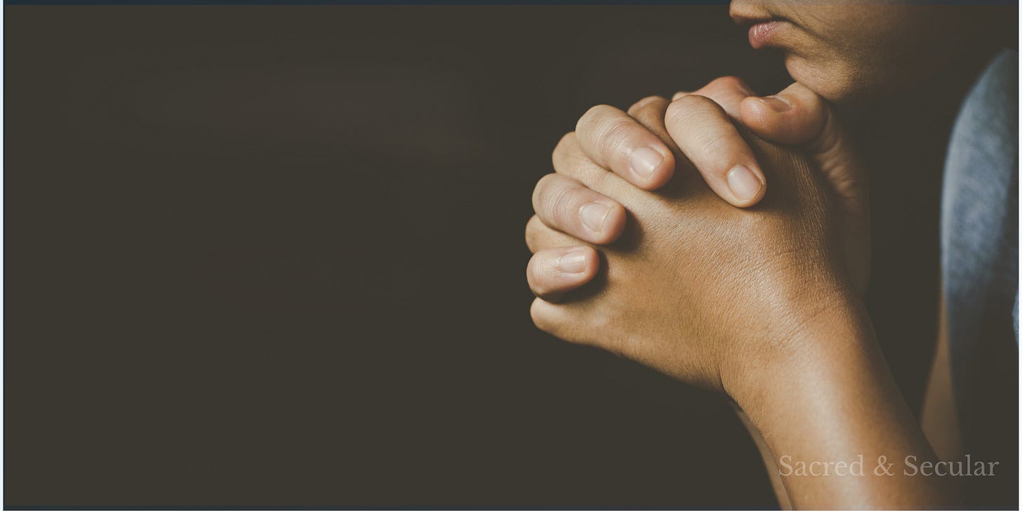 A person sits in quiet prayer with hands clasped together against a dark background, creating a reflective and contemplative atmosphere. A person sits in quiet prayer with hands clasped together against a dark background, creating a reflective and contemplative atmosphere.