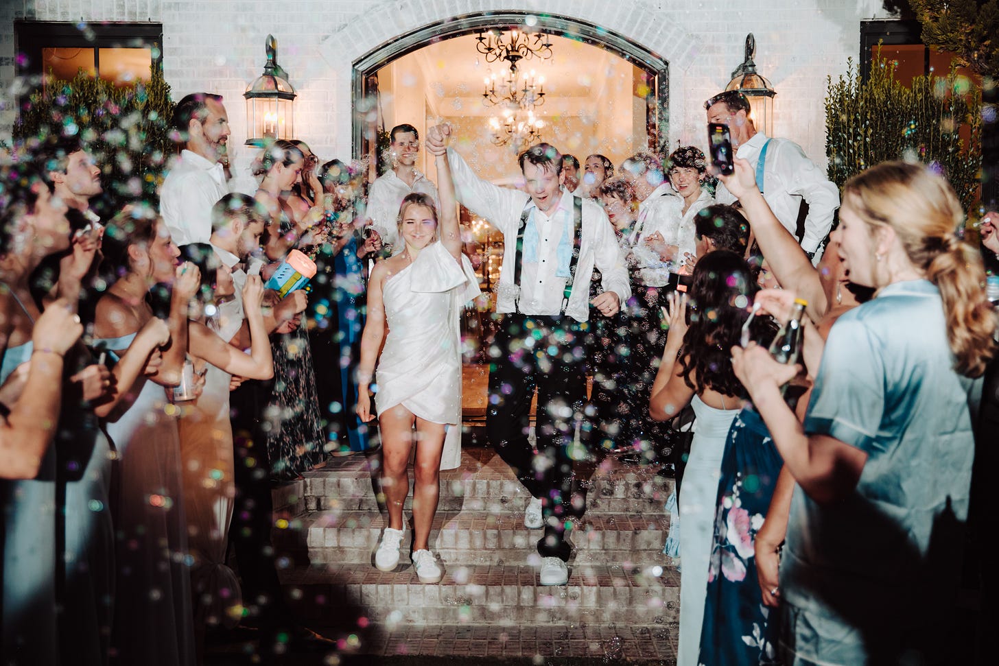 husband and wife leaving a wedding with bubbles in the air and people surrounding us