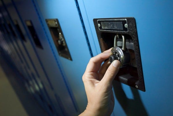 Opening a combination lock on a wall locker, finger turning dial.