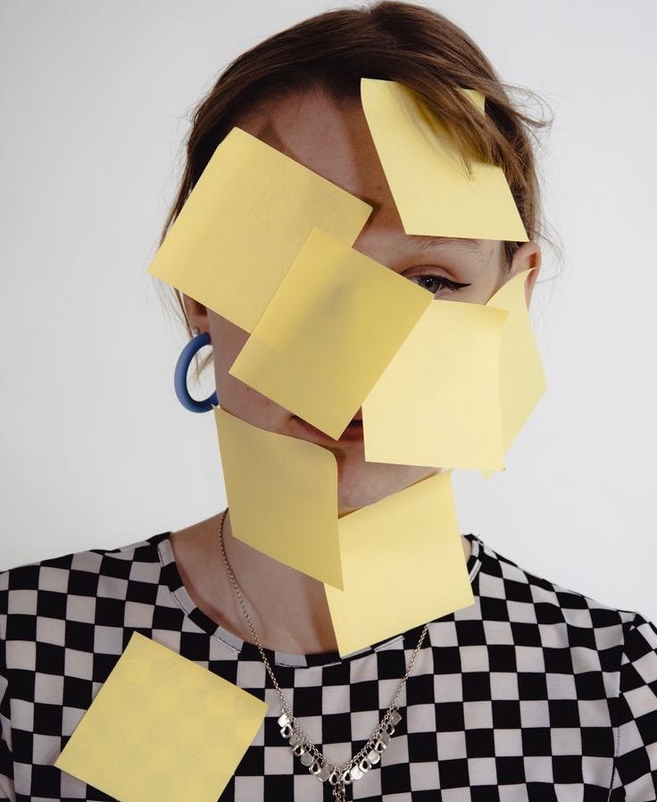 This may contain: a woman with yellow post it notes on her face