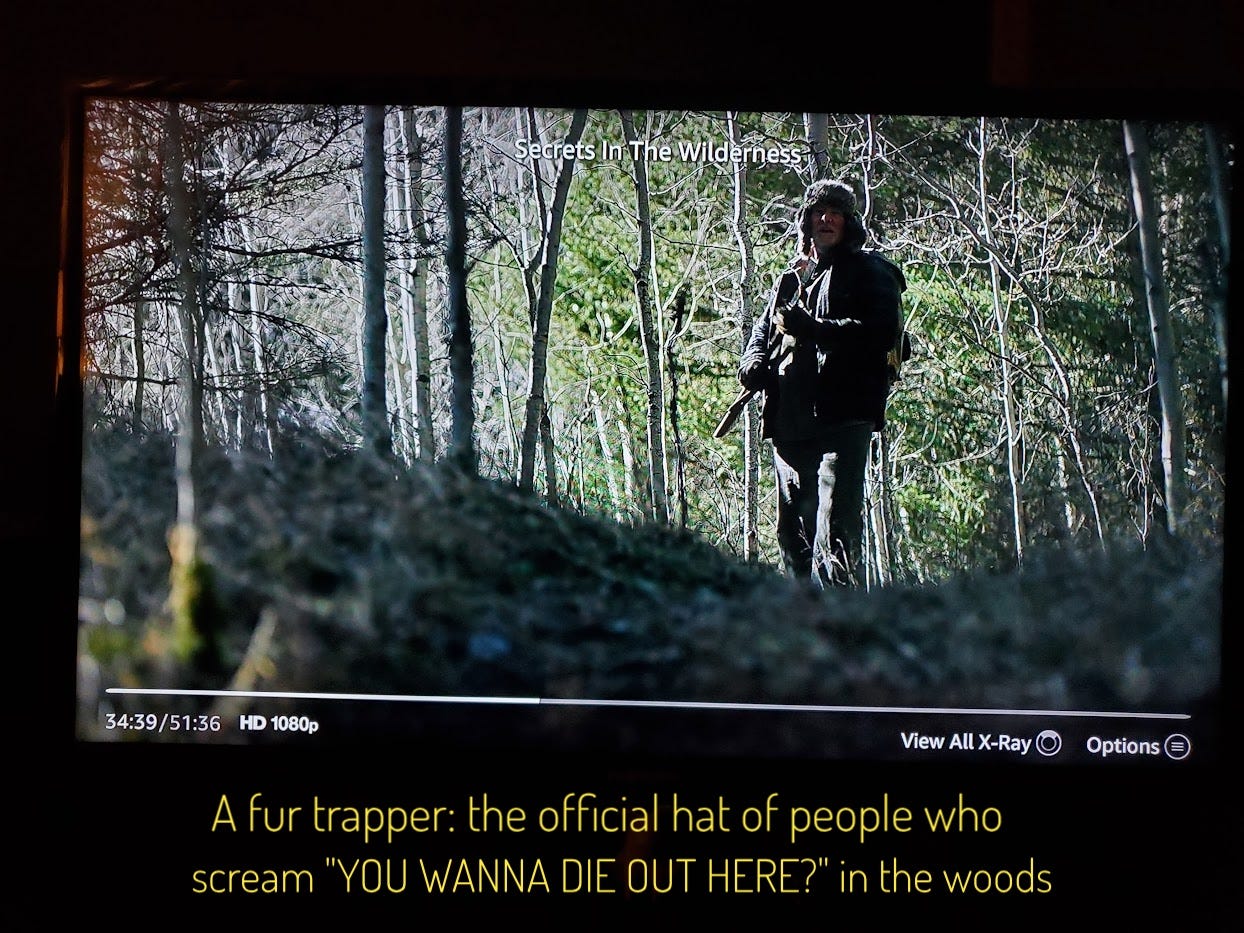 A dimly lit Tom O'Brien in wilderness gear and fur hat, captioned "A fur trapper: the official hat of people who scream 'YOU WANNA DIE OUT HERE?' in the woods"