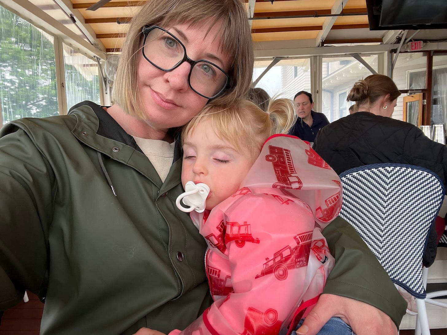 woman holds sleeping toddler in her lap