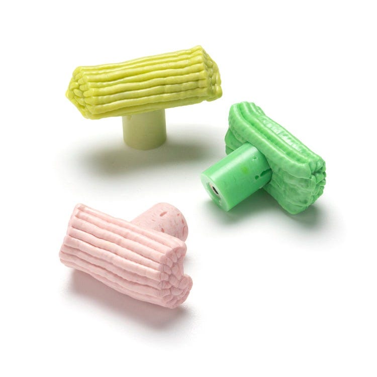 Three vibrant, pastel-colored Plastic Baroque Pull Handles from House of Voltaire are crafted in pink, green, and yellow using recycled materials and are arranged randomly on a white background. Each pull handle resembles a compact cluster of stacked tubes.