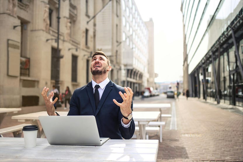 Image of a man sitting at a laptop in the street staring at the sky